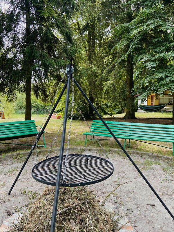 Palenisko z rusztem i ławkami wśród świerków